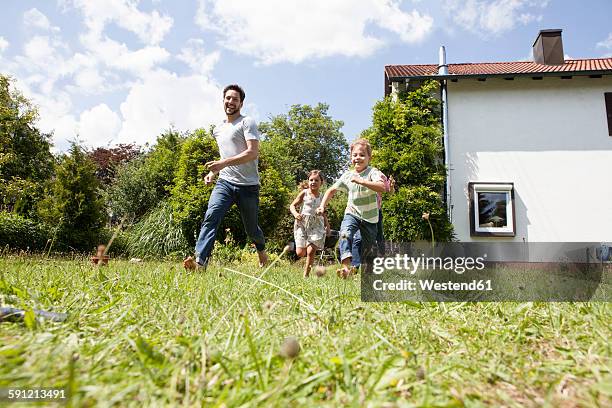 carefree family running in garden - familie haus stock-fotos und bilder