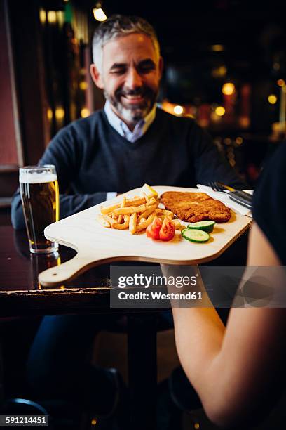 smiling man in restaurant receiving wiener schnitzel with french fries - wiener schnitzel stock pictures, royalty-free photos & images