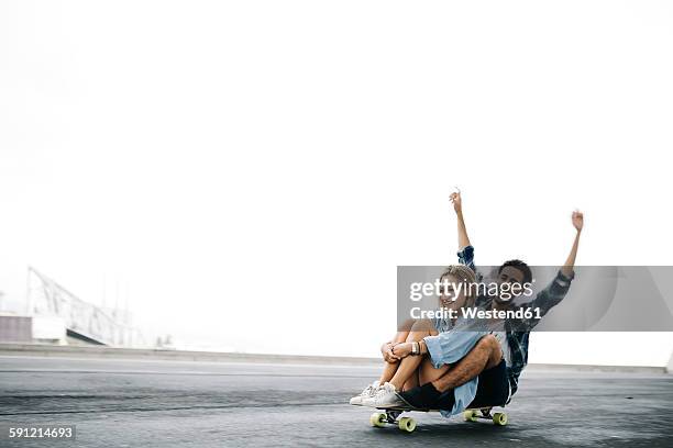 young couple cruising on a longboard - young man arms up stock-fotos und bilder