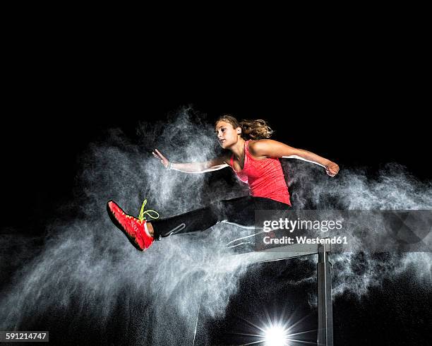 young woman jumping over hurdle in between cloud of flour - all purpose flour stockfoto's en -beelden