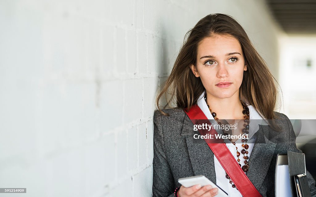 Young woman holding folder and cell phone