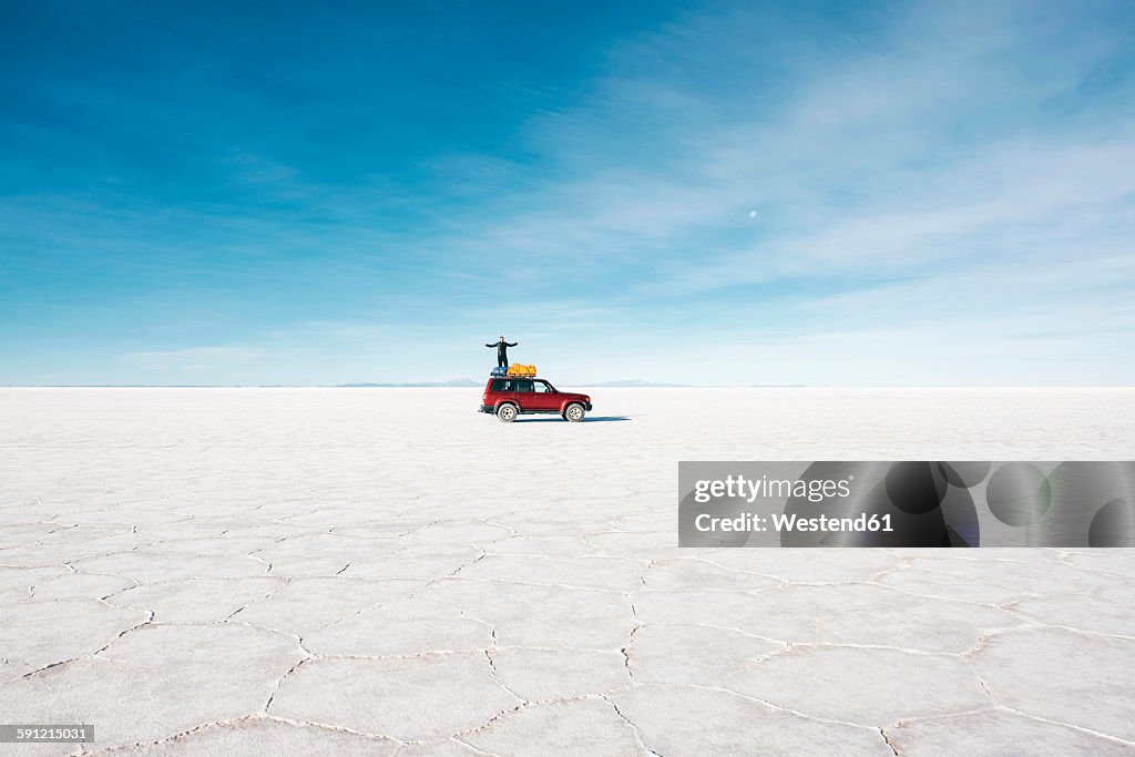 Bolivia, Potosi, man standing on his 4x4 in the Uyuni Salt Flats