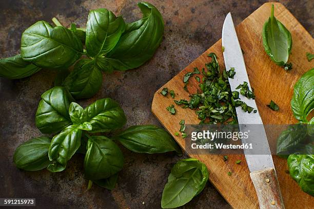 whole and chopped basil leaves and kitchen knife on wooden board - basil fotografías e imágenes de stock