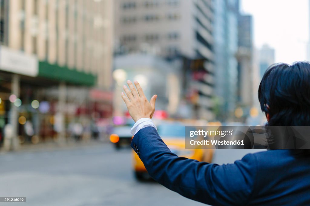 USA, New York City, businessman hailing a taxi