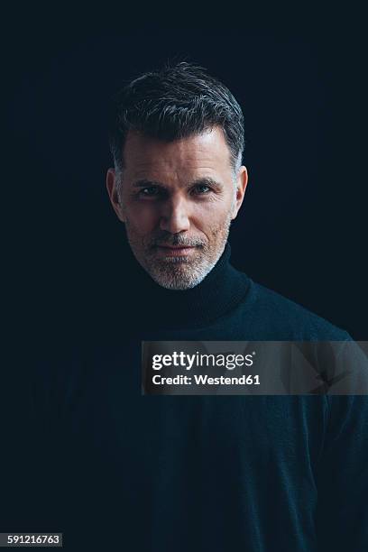 portrait of man wearing black turtleneck in front of black background - studio portrait dark background stock-fotos und bilder