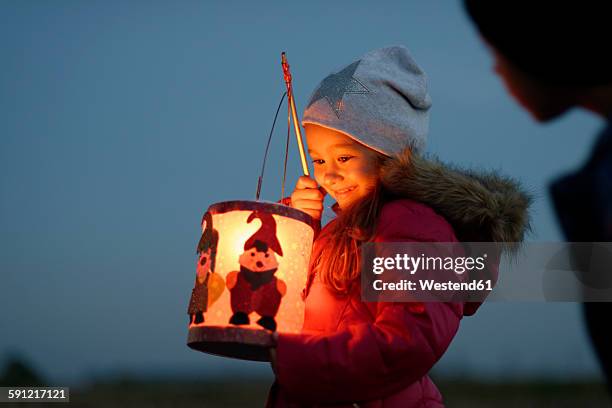 smiling little girl with self-made paper lantern in the evening - windlicht stock-fotos und bilder