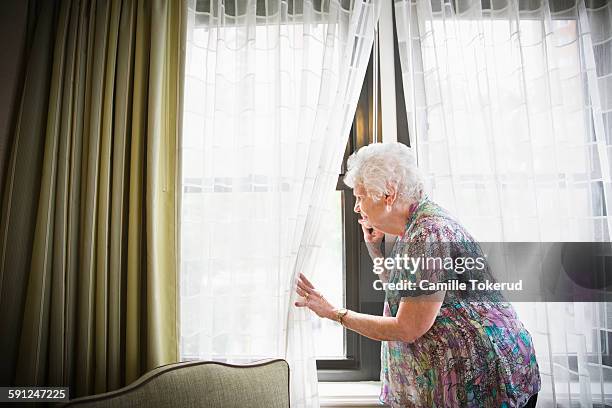 elderly woman looking out the window - old woman by window stock pictures, royalty-free photos & images