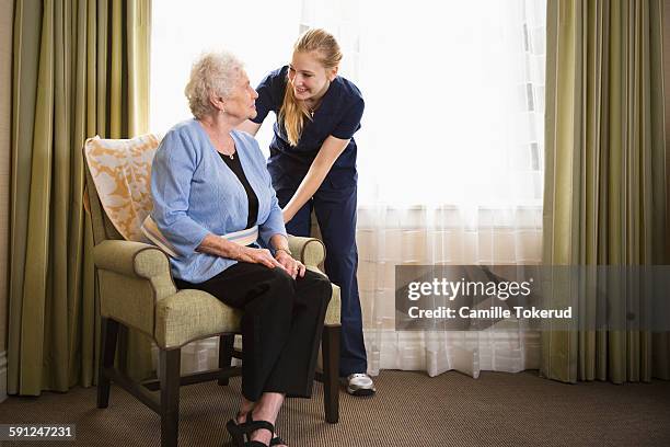 female nurse assisting elderly woman in livingroom - 80 plus years imagens e fotografias de stock