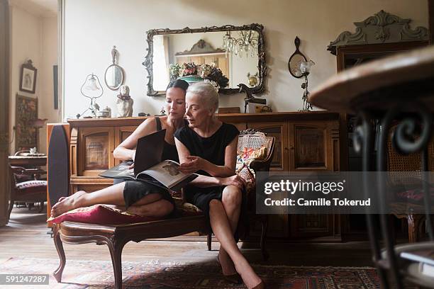 two fashionable women looking at photograph book - wealthy family inside home stock pictures, royalty-free photos & images