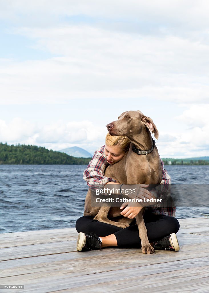 Girl hugging dog on dock