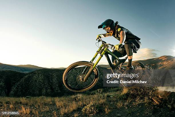 female biker jumping on her mountain bike. - bicicleta mountain bike fotografías e imágenes de stock