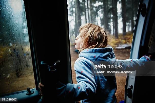 Girl leaning out door of camper van in the morning