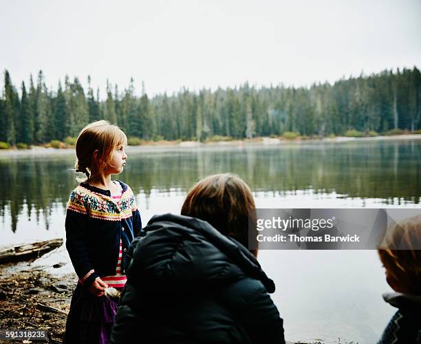 Girl standing on shoreline of lake with family
