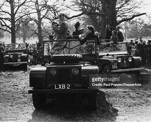 Queen Elizabeth II and Prince Philip, Duke of Edinburgh stand on the front seats of an open top Land Rover as they watch the Olympic Horse Trials at...