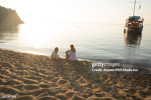 couple relax on beach, look out to sea at sunrise - look back 個照片及圖片檔