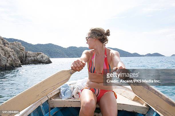 young woman paddles rowboat across calm sea waves - stadt antalya stock-fotos und bilder