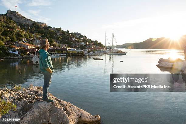 man looks out to sea and sunrise, from rock cliff - antalya province stock pictures, royalty-free photos & images