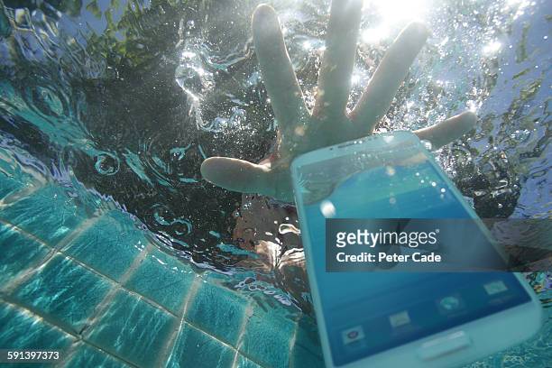 hand reaching for phone dropped in pool - damaged stock-fotos und bilder