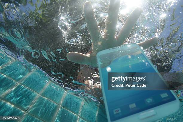 hand reaching for phone dropped in pool - sunken stock pictures, royalty-free photos & images