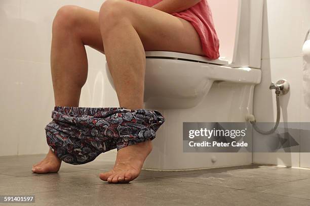 woman sat on toilet - urologie stock-fotos und bilder