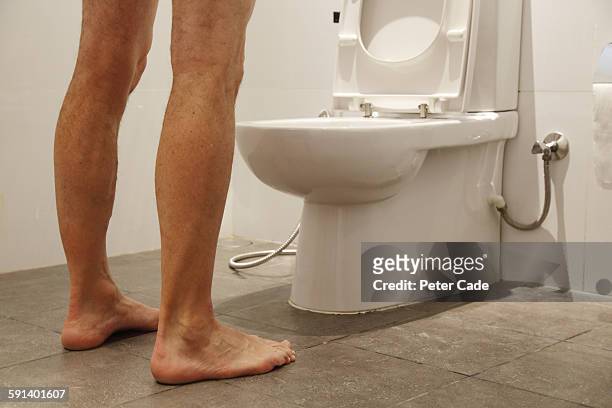 man stood over toilet - standing water fotografías e imágenes de stock