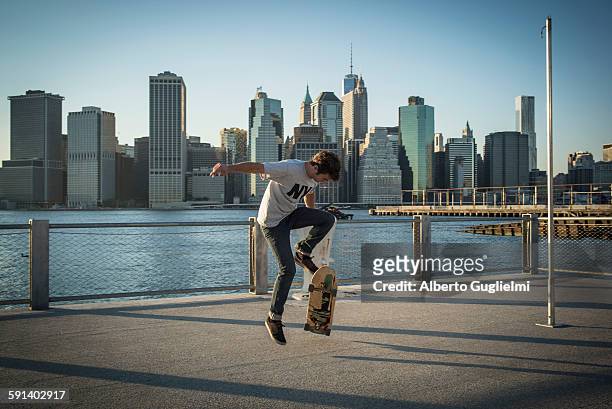 caucasian skateboarder doing trick at waterfront, new york, united states - alberto stock-fotos und bilder