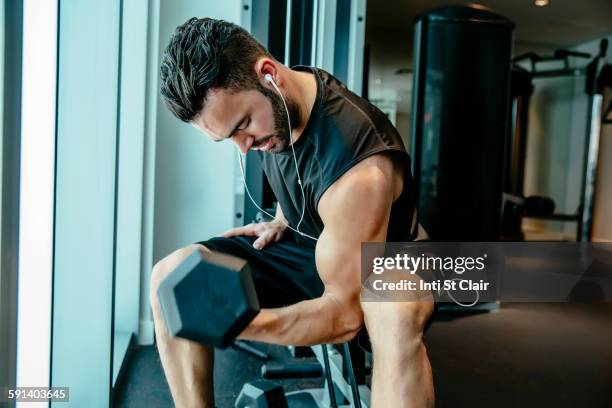 man lifting weights in gymnasium - man lifting dumbbell stock pictures, royalty-free photos & images