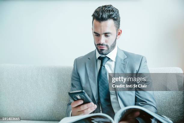 businessman using cell phone on sofa - mixed magazine foto e immagini stock