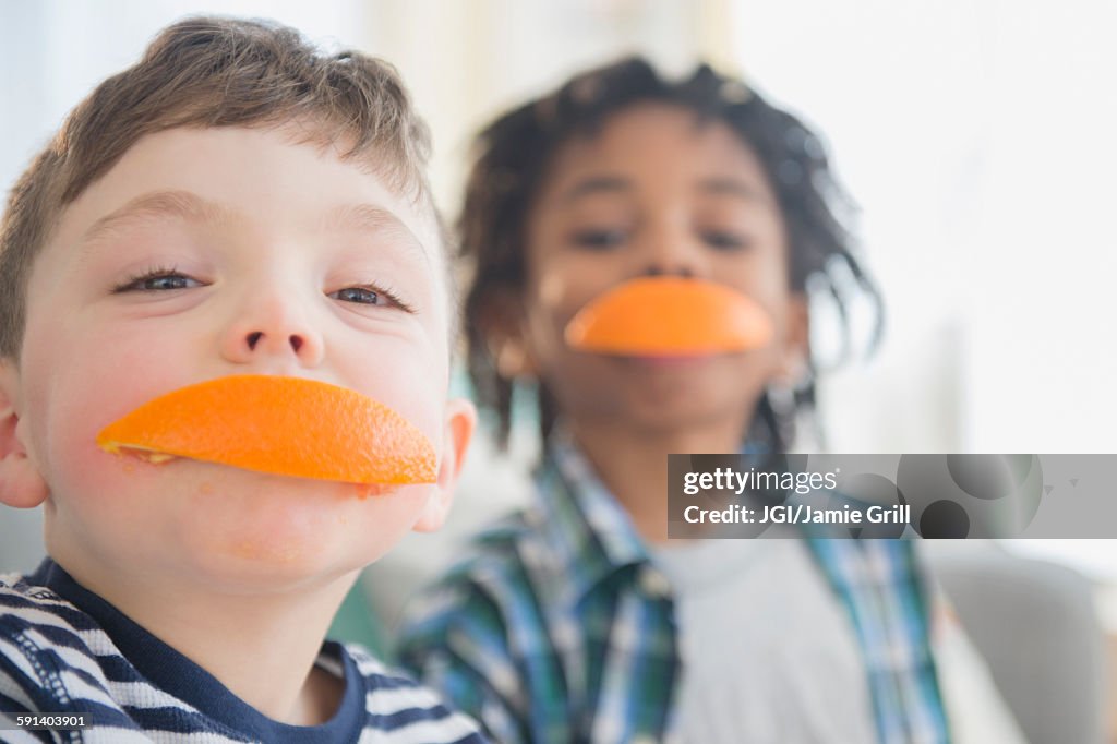 Boys biting orange slices
