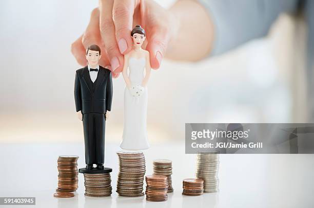mixed race woman balancing bride and groom statues on coin stacks - coniugi foto e immagini stock