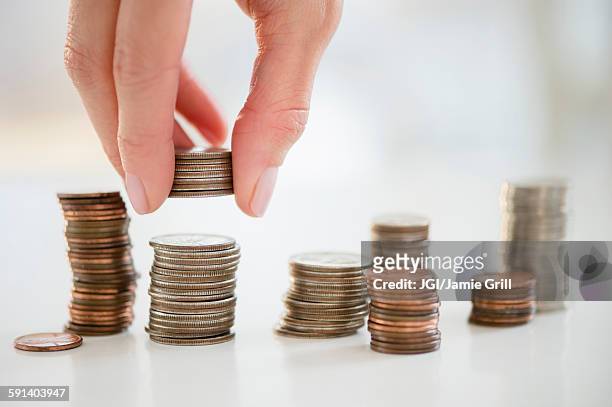 mixed race woman stacking coins - positioned stock pictures, royalty-free photos & images