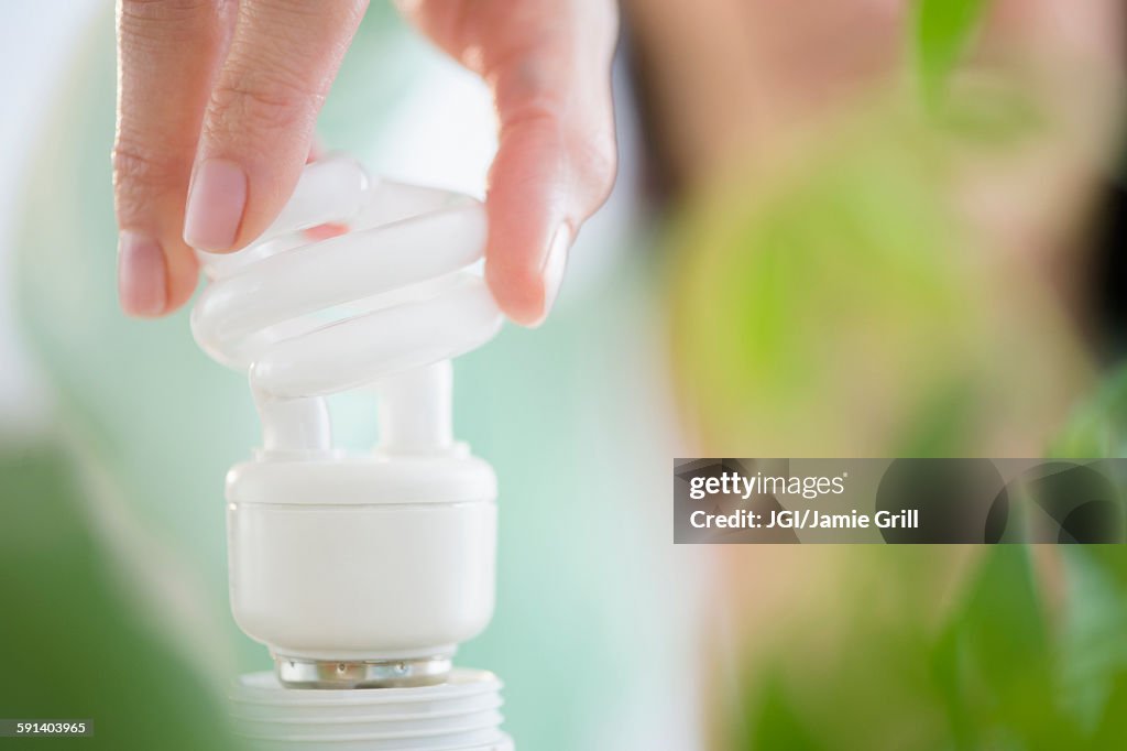 Mixed race woman holding fluorescent light bulb