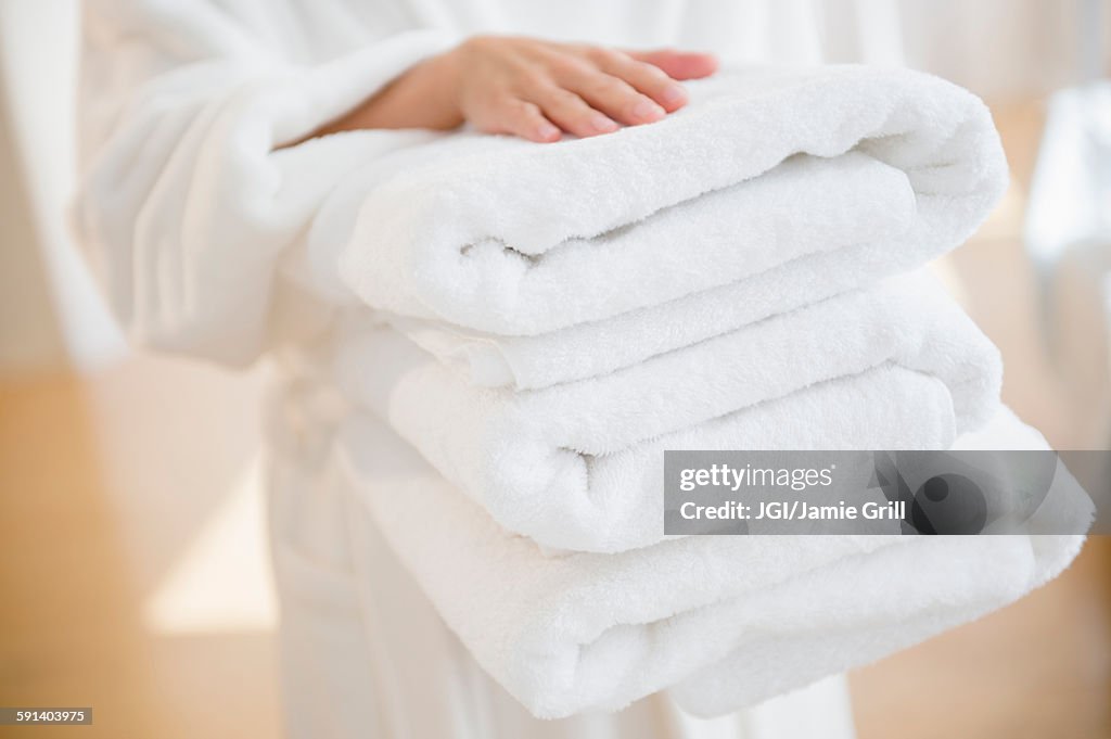 Mixed race woman carrying stack of clean towels