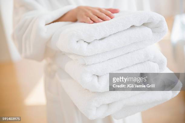 mixed race woman carrying stack of clean towels - towel stock pictures, royalty-free photos & images