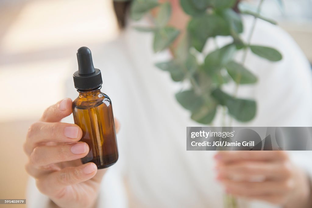 Mixed race woman holding bottle of essential oil