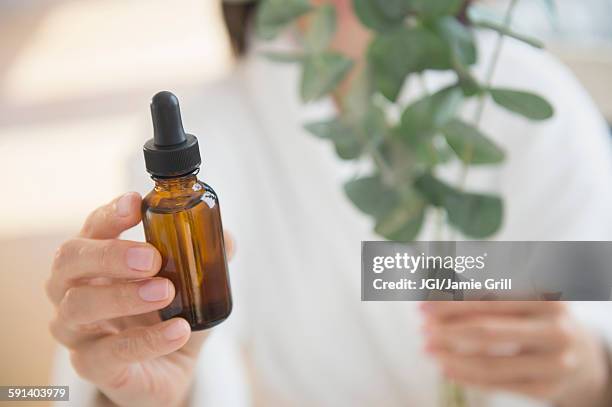 mixed race woman holding bottle of essential oil - eucalyptus tree stock pictures, royalty-free photos & images