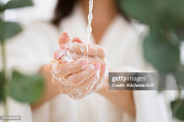 mixed race woman washing her hands in water - foam hand stockfoto's en -beelden