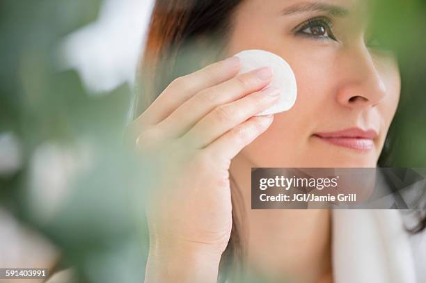 mixed race woman patting makeup on face - wattepad stock-fotos und bilder