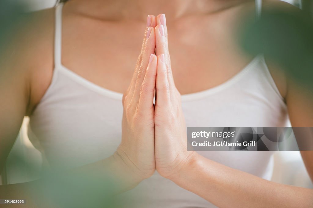 Mixed race woman meditating with clasped hands
