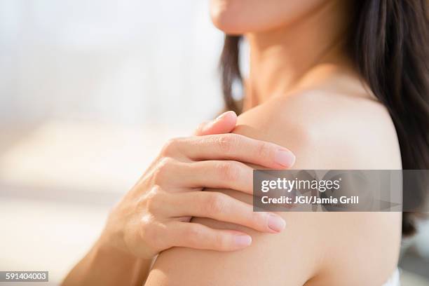 mixed race woman rubbing lotion into skin - shoulder ストックフォトと画像