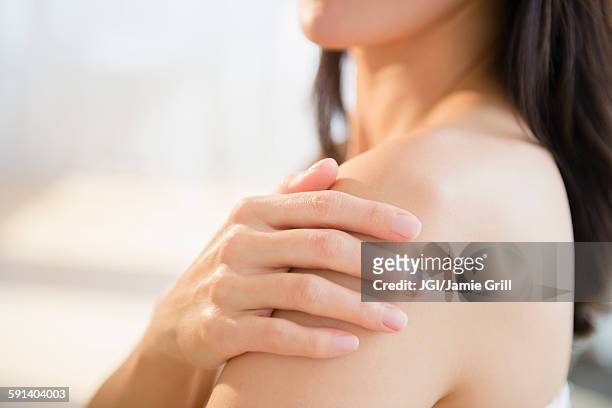 mixed race woman rubbing lotion into skin - rubbing stock pictures, royalty-free photos & images