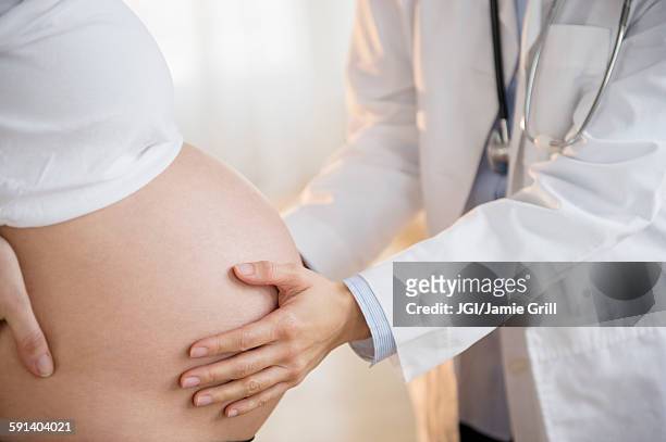 doctor examining belly of pregnant woman - prenatal care stockfoto's en -beelden