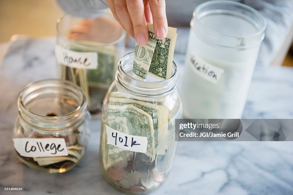 Mixed race woman saving money in jars