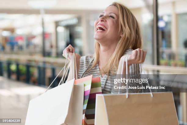 mixed race woman carrying shopping bags in mall - tote bag white stock pictures, royalty-free photos & images