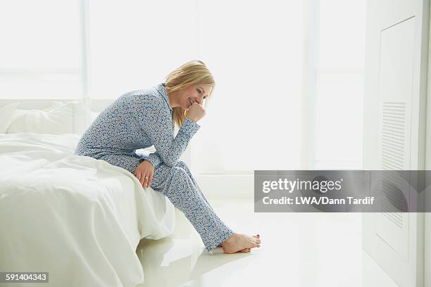 caucasian woman sitting on bed - lwa dann tardif bed stock pictures, royalty-free photos & images