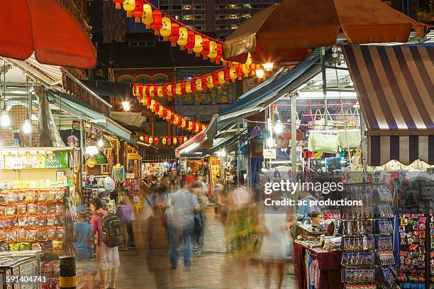 blurred view of people shopping in outdoor market at night - singapore night market stock pictures, royalty-free photos & images