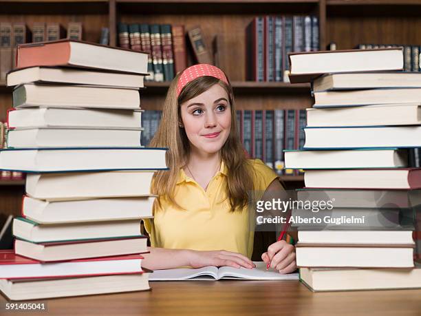 student with stacks of books at desk in library - conservative stock-fotos und bilder
