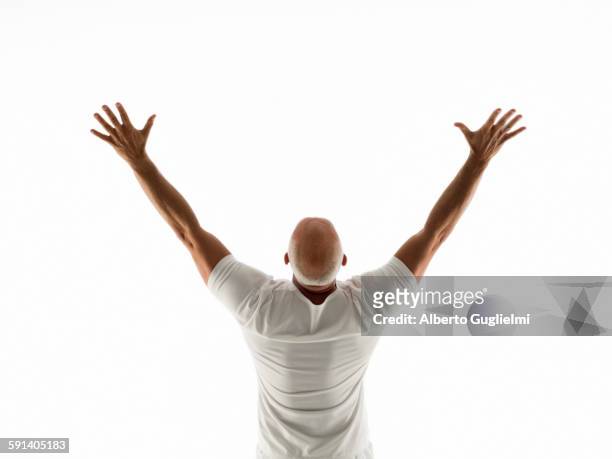 rear view of older man cheering with arms raised - braccia alzate foto e immagini stock