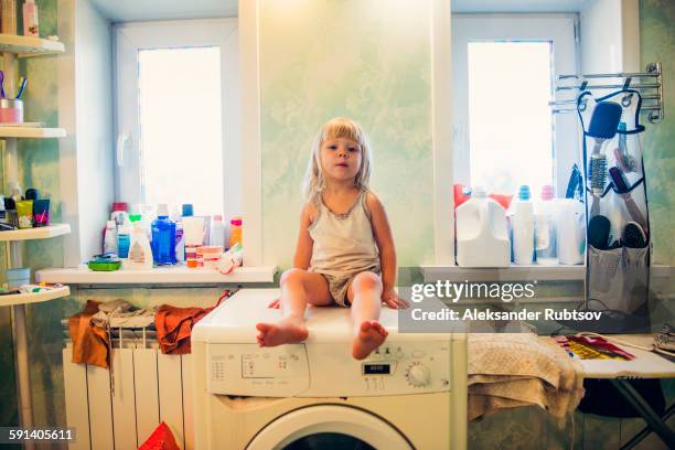 caucasian girl sitting on washing machine - abstellraum stock-fotos und bilder