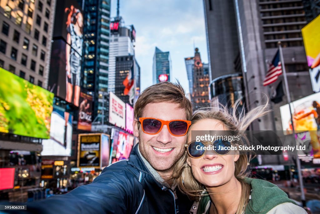 Caucasian couple taking selfie in Times Square, New York City, New York, United States